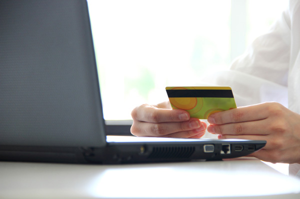 Using computer with credit card in hand