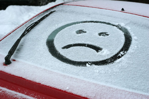Sad face on car window in snow