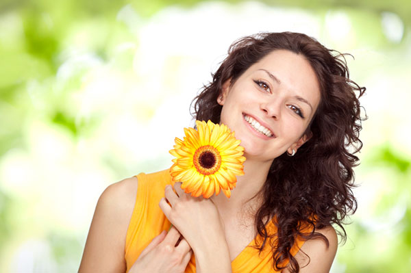Smiling woman holding a sunflower | Sheknows.com