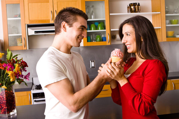 Couple with cupcake in kitchen