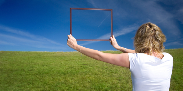 Woman with frame on big meadow