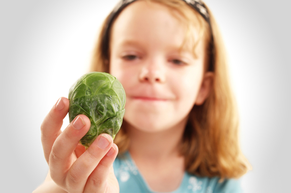 Girl looking at brussels sprout