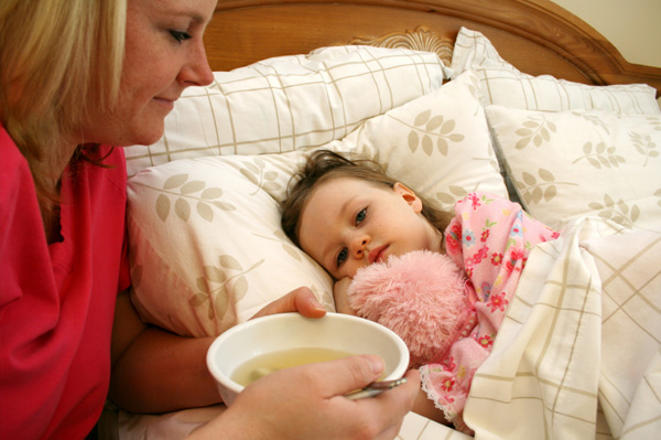 Mom giving sick child soup
