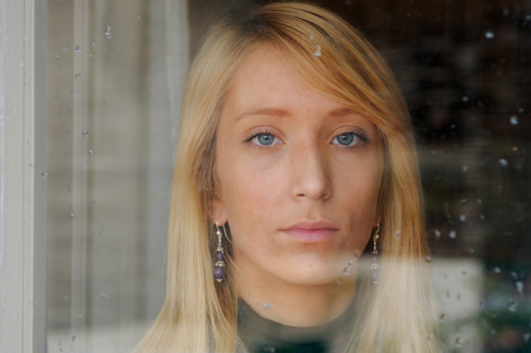 Sad woman looking through winter window