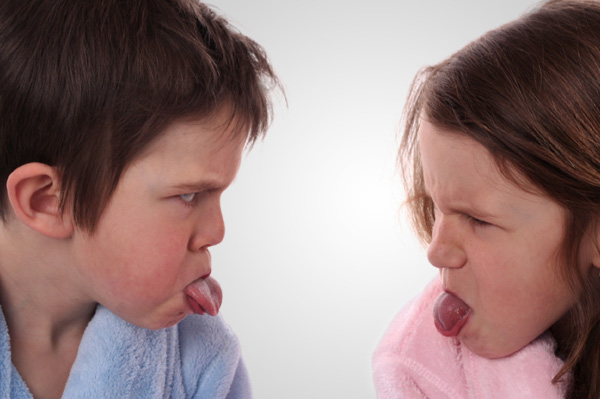 Siblings sticking out tongue at each other