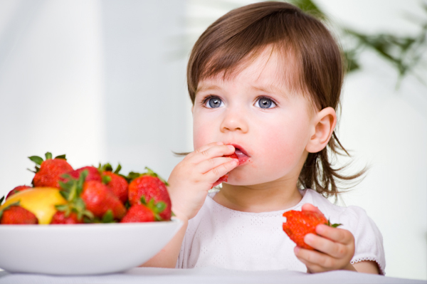 Toddler girl eating strawberry