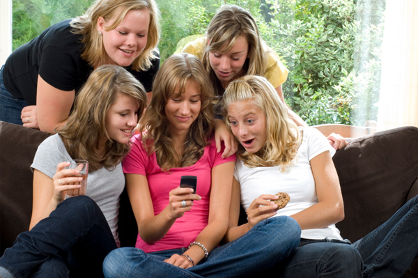 Tweens looking at cell phone