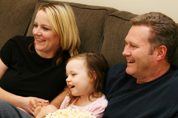 Woman laughing and watching tv with family