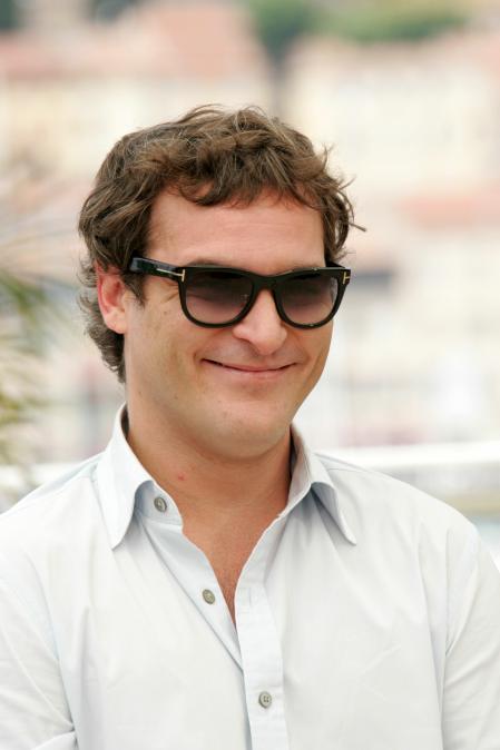 Joaquin Phoenix is wearing sunglasses and smiling