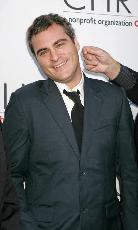Joaquin Phoenix with a dark suit and black tie at a nonprofit organization event