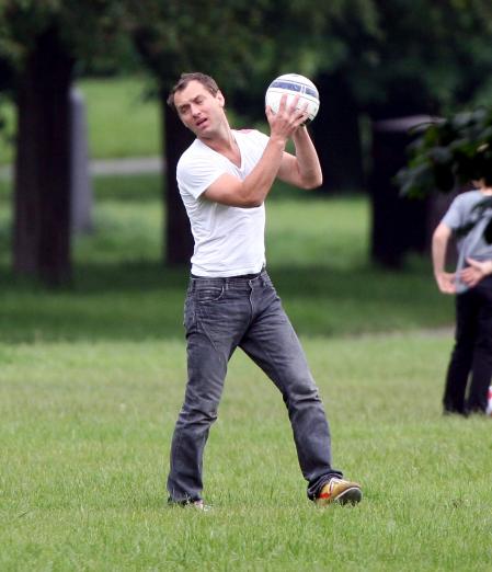 Jude Law in the grass holding a soccer ball while in London