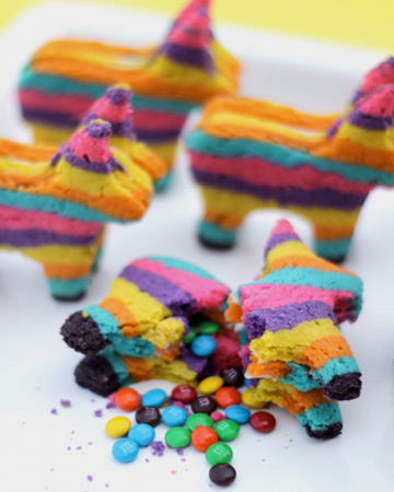 3 pinata cookies made out of multicolored cookies filled with mini m&m's.