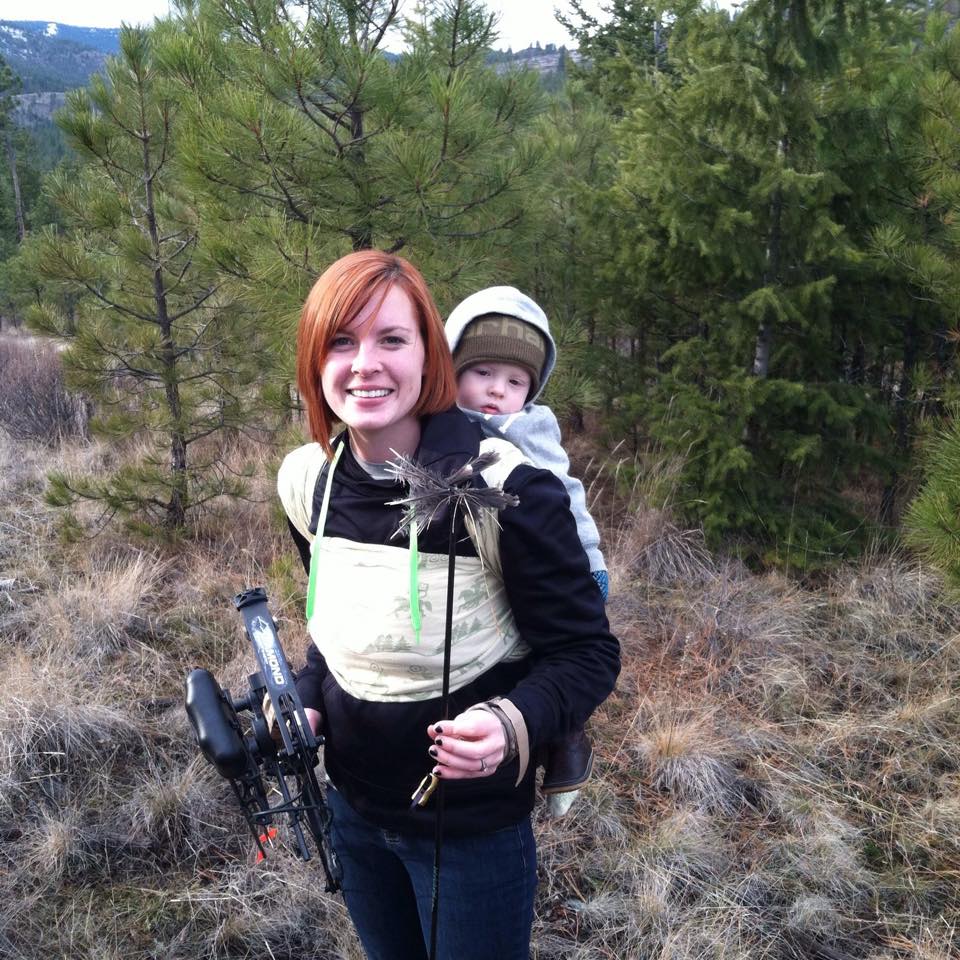 Mom in mountains babywearing with bow