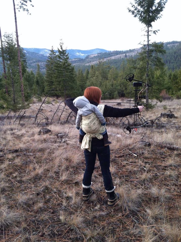 Tara babywearing as she shoots a bow